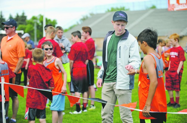 High Five Flyers sprint coach Bryce Frazee gives a good luck fist bump to Carson Chastain, 11, before he runs the 400 meter dash during the youth track club tri-meet on Thursday at Ravsten Stadium. Frazee is a 2015 Idaho Falls High School graduate and current sprinter at the Colorado School of Mines. Pat Sutphin / psutphin@postregister.com